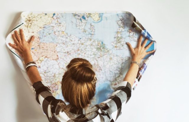 A woman holding a poster map up against a wall 