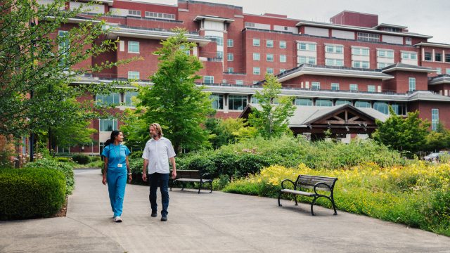 two caregivers walking outside in front of peacehealth sacred heart medical center
