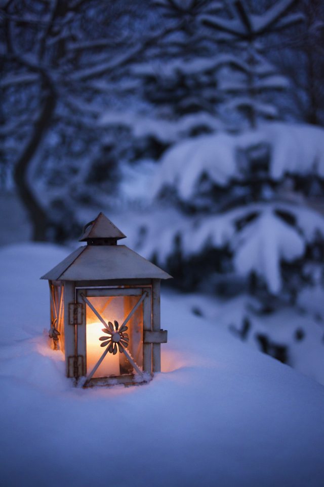A lit lantern exposed in a bank of snow