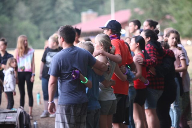 A group of people with their backs to the camera and their arms around each other