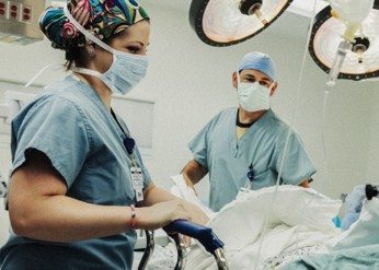 two caregivers standing next to a patient bed looking at the patient