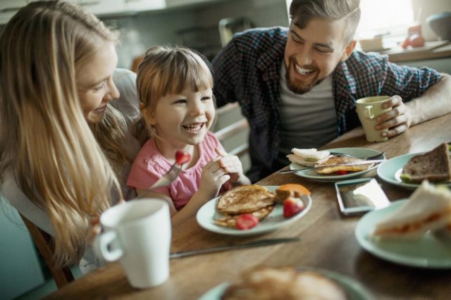 A family sits at the food table, enjoying breakfast and laughing
