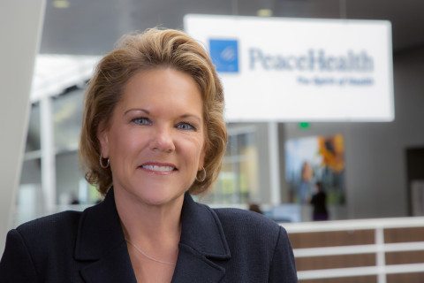 Kim Hodgkinson smiles while standing in front of a PeaceHealth sign