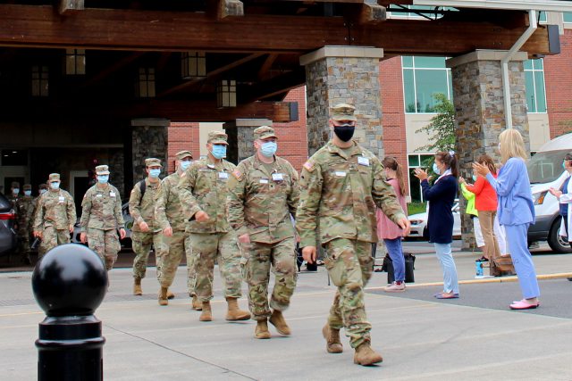 A group of PeaceHealth staff claps for National Guard members as they exit the hospital. 