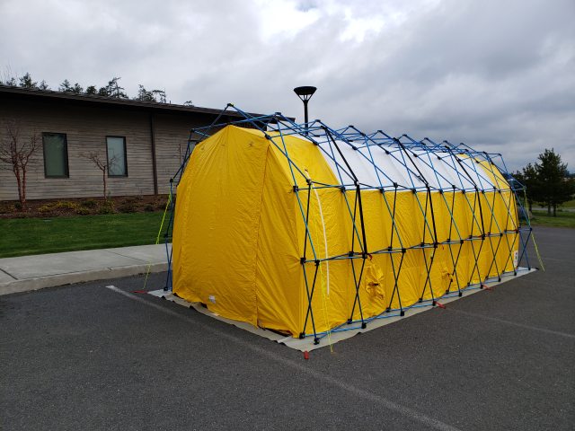 A large yellow tent sits in a parking lot