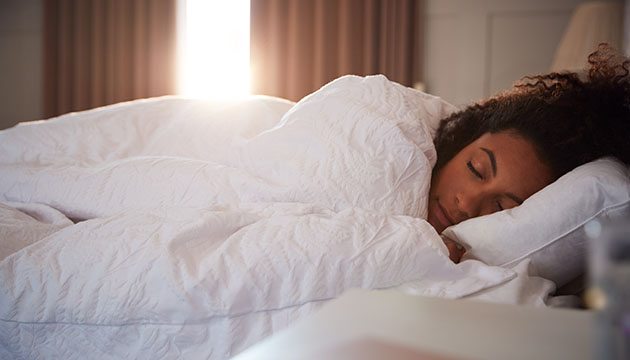 woman sleeping in bed as morning dawns