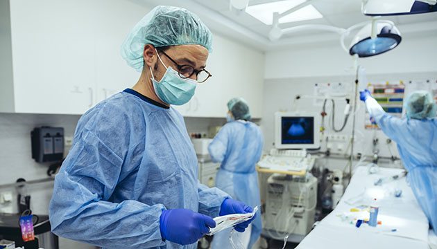 Doctor holds an IV bag in a procedure room