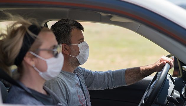 man and woman wearing masks in the car