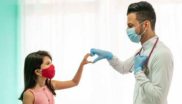 Young person in a mask makes heart sign with doctor in a mask
