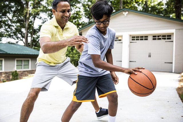 Adult and kid playing basketball.