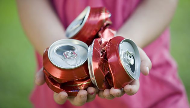 person holding crushed soda cans