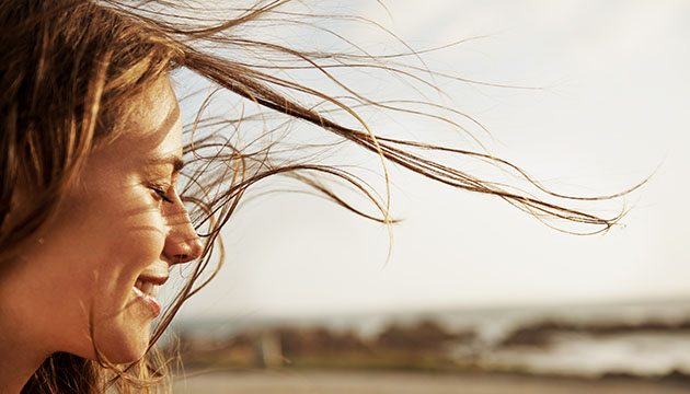 A woman smiles as her hair gently sways in the wind