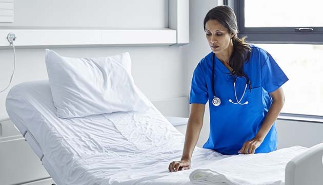 nursing assistant making a hospital bed