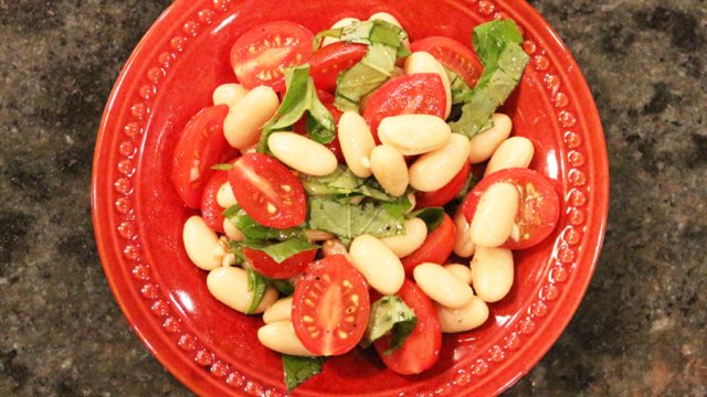 Mediteranean bean salad in an orange bowl