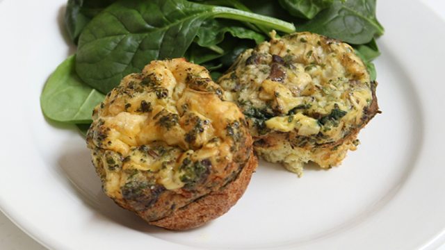 Egg stuffed mushrooms and baby spinach on a white plate