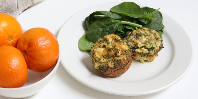 Egg stuffed mushrooms and baby spinach on a white plate