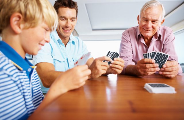 Three generations of men playing cards on a wooden table