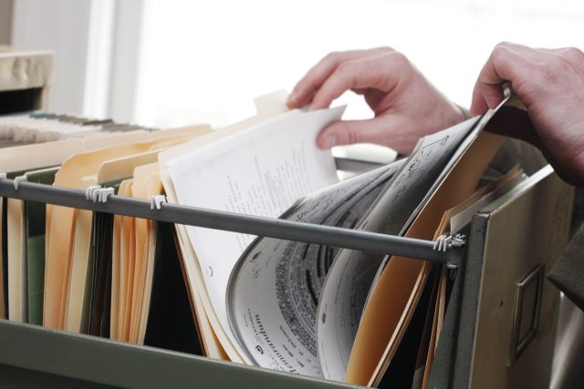 Hands going through documents in a filing cabinet