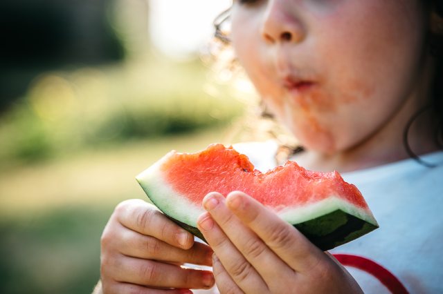 A young girl enjoys a slice of watermelon