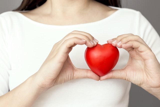 A person holds a heart shaped item in front of their chest