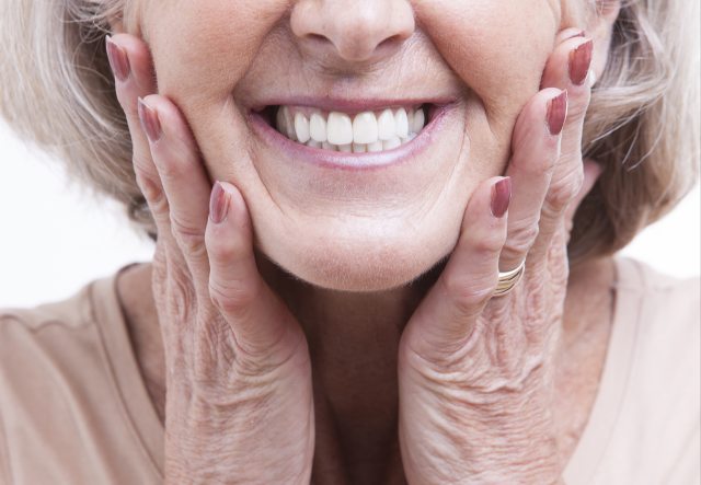 Older woman with a big smile resting her head on her hands