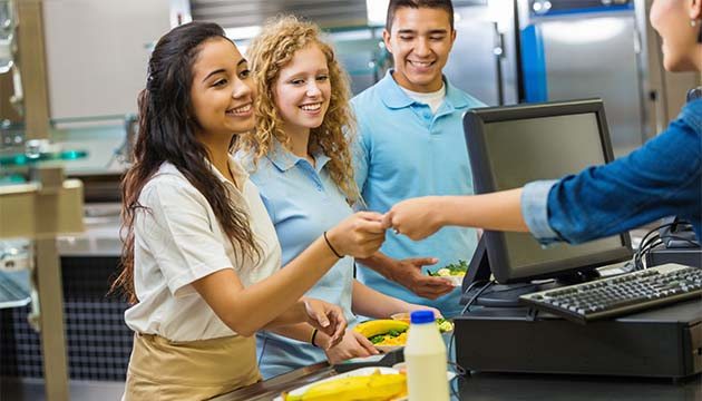 Young adults working in a cafeteria smile as one of the workers and customers interact
