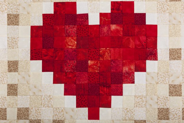 A quilt with an embroidered red heart