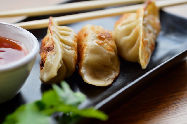 Potstickers sitting on a plate next to sauce