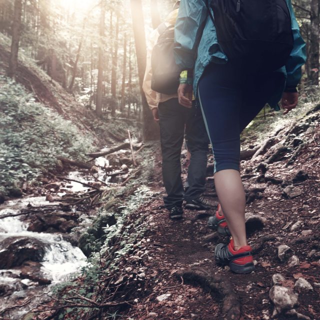 Two hikers traversing a creek in the woods