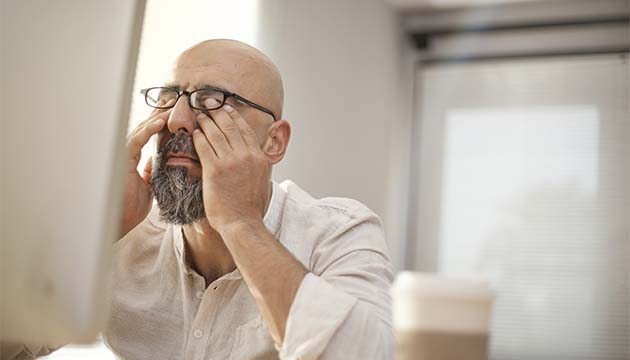 A man rubbing his eyes under his glasses