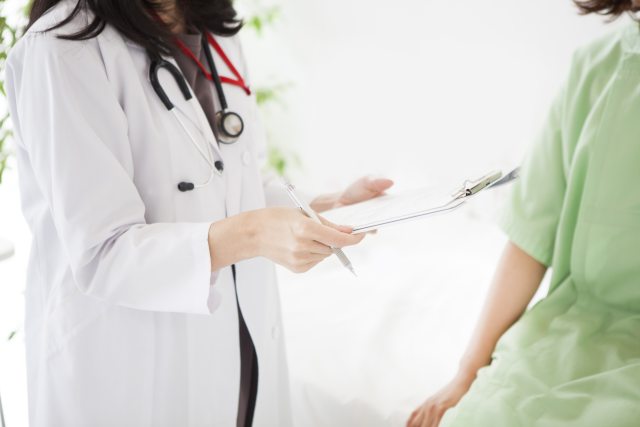 A provider holds a chart while talking with a patient