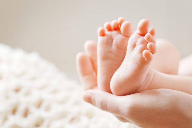 Adult hand holding a baby's feet