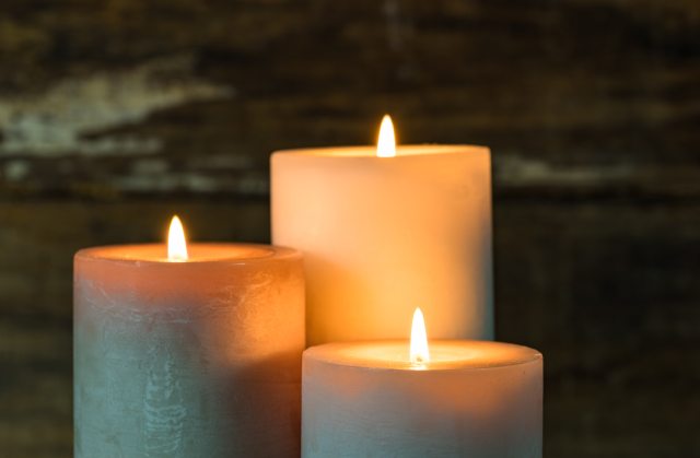 Three lit white candles providing ambient light