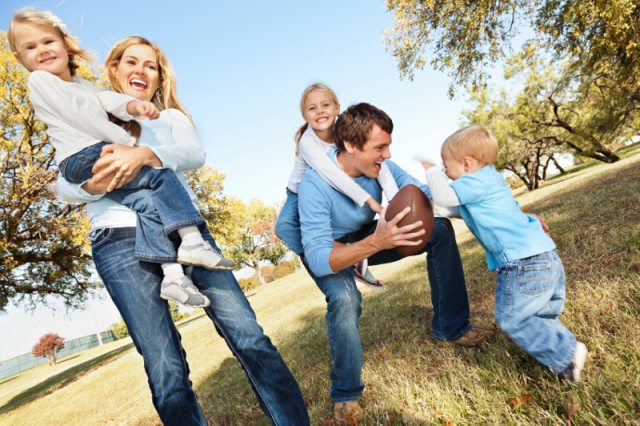 A family posing for photos in an outdoor setting while also playing football