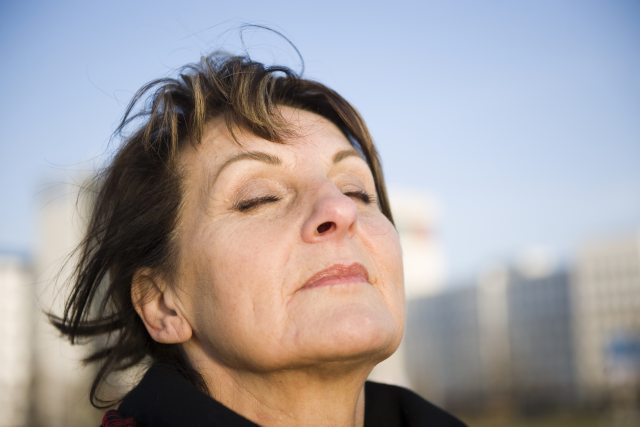 A woman closing her eyes and holding her face up towards the sky