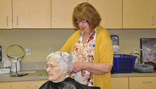 PeaceHealth volunteer trims the hair of nursing home resident