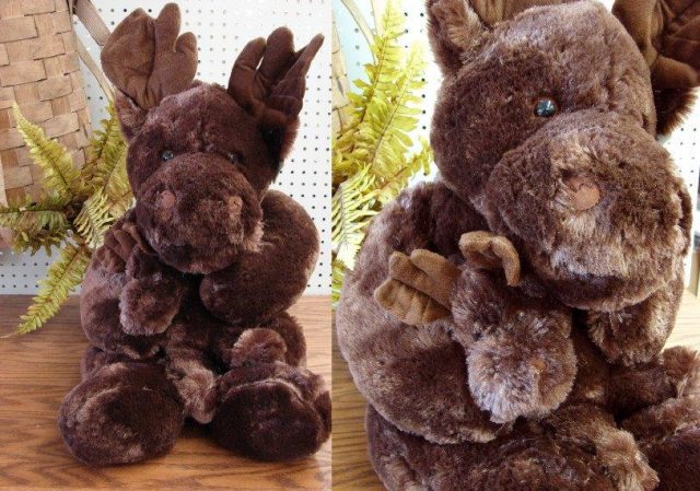 Stuffed plush moose rests on a table with fern in background