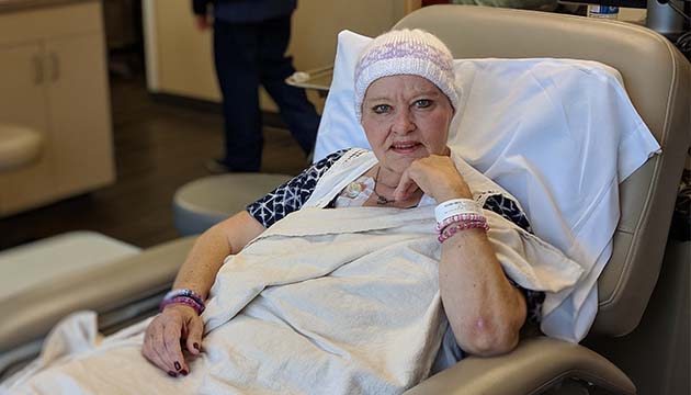 A woman looks at the camera from a patient bed