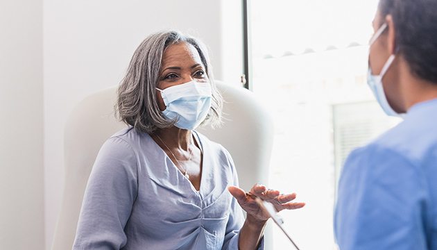Older woman in mask talks with a doctor